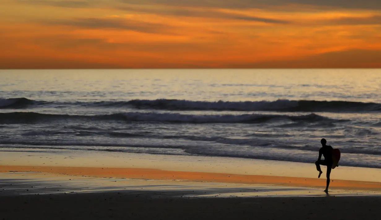 Pemain surfing saat menikmat matahari terbenam di Cardiff, California (27/1/2016). Wilayah Selatan California ini usai di landa Badai El Nino. (REUTERS/Mike Blake)
