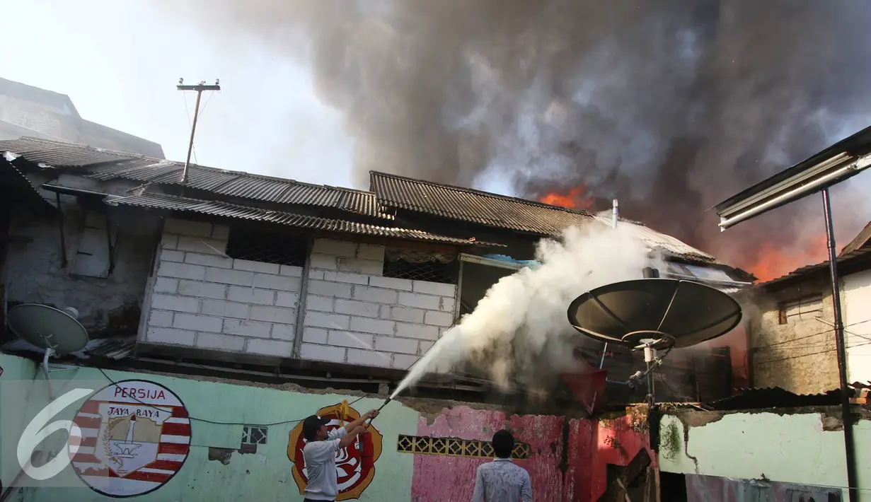 Warga menggunakan tabung pemadam untuk memadamkan api di kawasan Tanah Abang, Jakarta, Senin (5/9). Belum diketahui penyebab serta kerugian akibat kebakaran yang menghanguskan kawasan padat penduduk tersebut. (Liputan6.com/Immanuel Antonius)