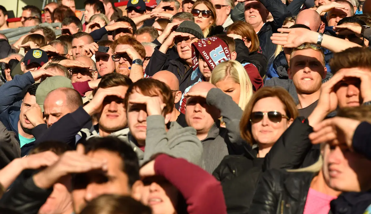 Fans Burnley menutup wajah karena terkena pancaran matahari saat menyaksikan timnnya melawan Arsenal pada lanjutan Premier League pekan ke-7 di Stadion Turf Moor, (2/10/2016). (Reuters/Anthony Devlin)