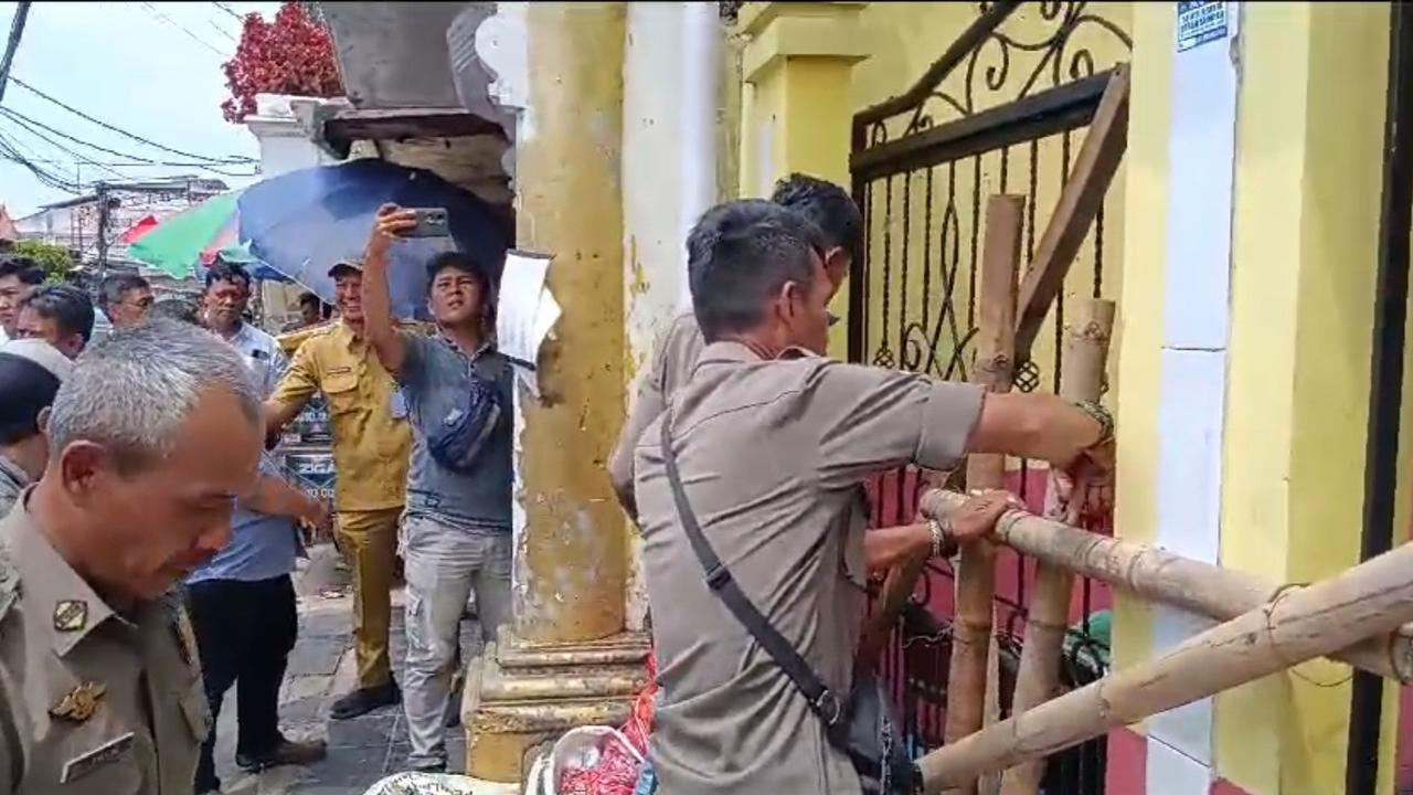 Anggota Satpol PP Kota Depok membuka segel sepihak yang dilakukan ahli waris dari lahan SDN Utan Jaya, Cipayung, Depok. (Istimewa)