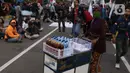 Pedangang menawarkan dagangannya kepada massa aksi saat demo penolakan omnibus law di kawasan patung kuda, Jakarta, Selasa (20/10/2020). Para pedagang kaki lima memanfaatkan moment aksi massa untuk mencari ke untungan meskupun sangat membahayakan bagi keselamatan mereka. (Liputan6.com/Angga Yuniar)