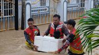 Aparat Polda Sulut dan Basarnas Manado mengevakuasi seorang balita yang terjebak banjir di Manado, Jumat (27/1/2023).