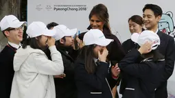 Para siswa menyambut Ibu Negara AS, Melania Trump ditemani personel boyband SHINee, Choi Min-ho pada acara 'Girls Play 2!', kampanye Olimpiade Musim Dingin PyeongChang 2018, di Kedutaan Besar AS di Seoul, Selasa (7/11). (AP Photo/Ahn Young-joon. Pool)