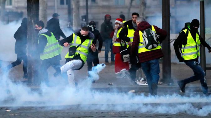 Demonstran menendang tabung gas air mata saat kerusuhan menentang kenaikan harga bahan bakar di Paris, Prancis, Sabtu (24/11). Polisi menggunakan gas air mata dan meriam air untuk membubarkan demonstran. (AP Photo/Christophe Ena)