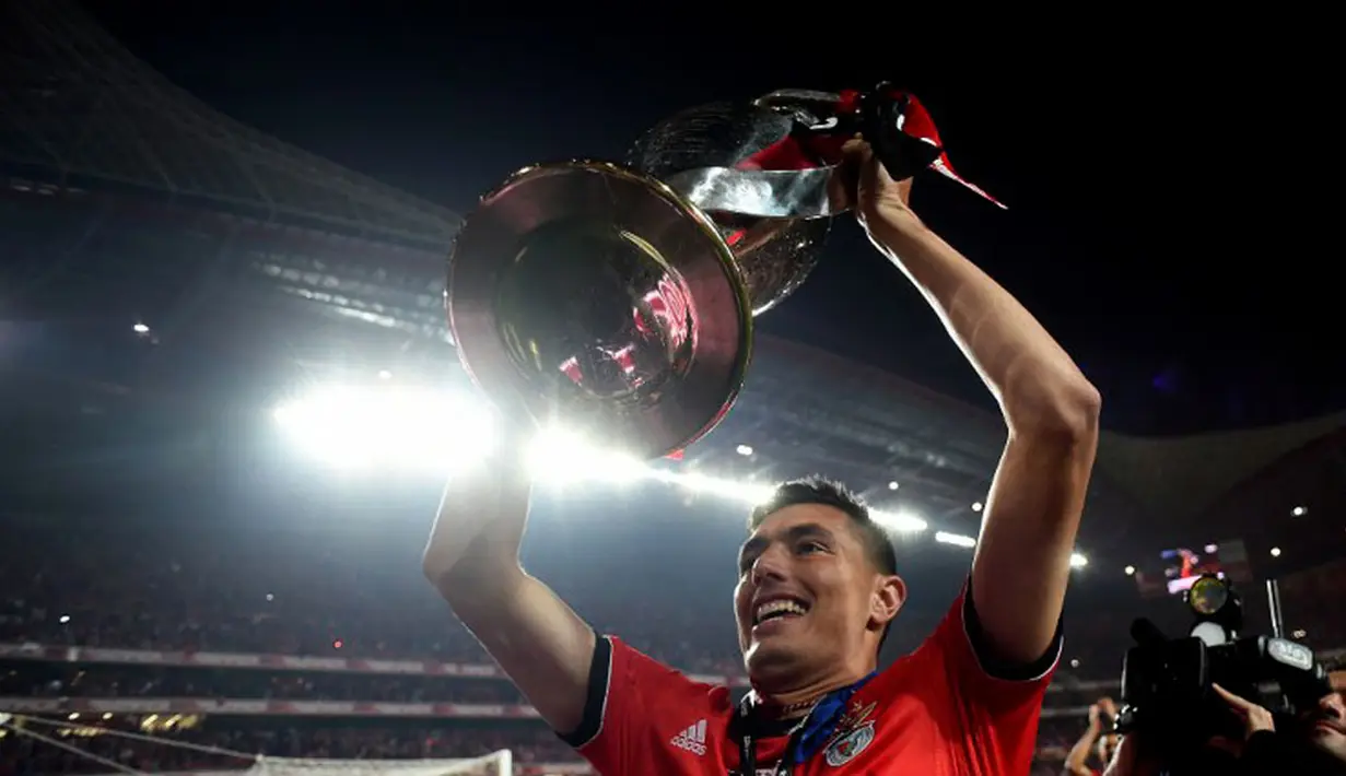 Pemain depan Benfica, Oscar Cardozo, mengangkat trofi saat merayakan gelar liga ke-33 bagi "the eagles" di Estadio Da Luz, Lisbon, Senin (21/4/2014) (AFP PHOTO/FRANCISCO LEONG)