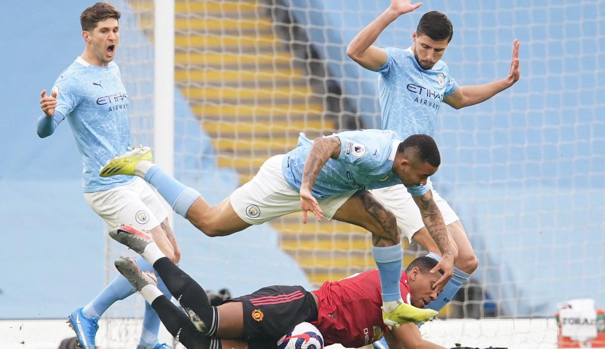 Striker Manchester United, Anthony Martial (bawah) dijatuhkan striker Manchester City, Gabriel Jesus di kotak penalti dalam laga lanjutan Liga Inggris 2020/21 di Etihad Stadium, Minggu (7/3/2021). MU menang 2-0 atas Mancity. (AFP/Dave Thompson/Pool)