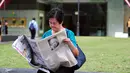 Seorang wanita membaca koran setelah sehari meninggalnya mantan PM Singapura, Lee Kuan Yew, Singapura, Selasa (24/3/2015). Lee meninggal pada hari Senin (23/3) di usia 91 tahun dan wajahnya menghiasi berbagai media cetak Singapura. (AFP PHOTO/Mohd FYROL)