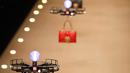 Pesawat tanpa awak (drone) keluar dari belakang panggung sembari terbang membawa koleksi tas musim gugur Dolce & Gabbana pada Milan Fashion Week 2018, Minggu (25/). Aksi yang tak biasa ini membuat para tamu terkejut. (Miguel MEDINA/AFP)