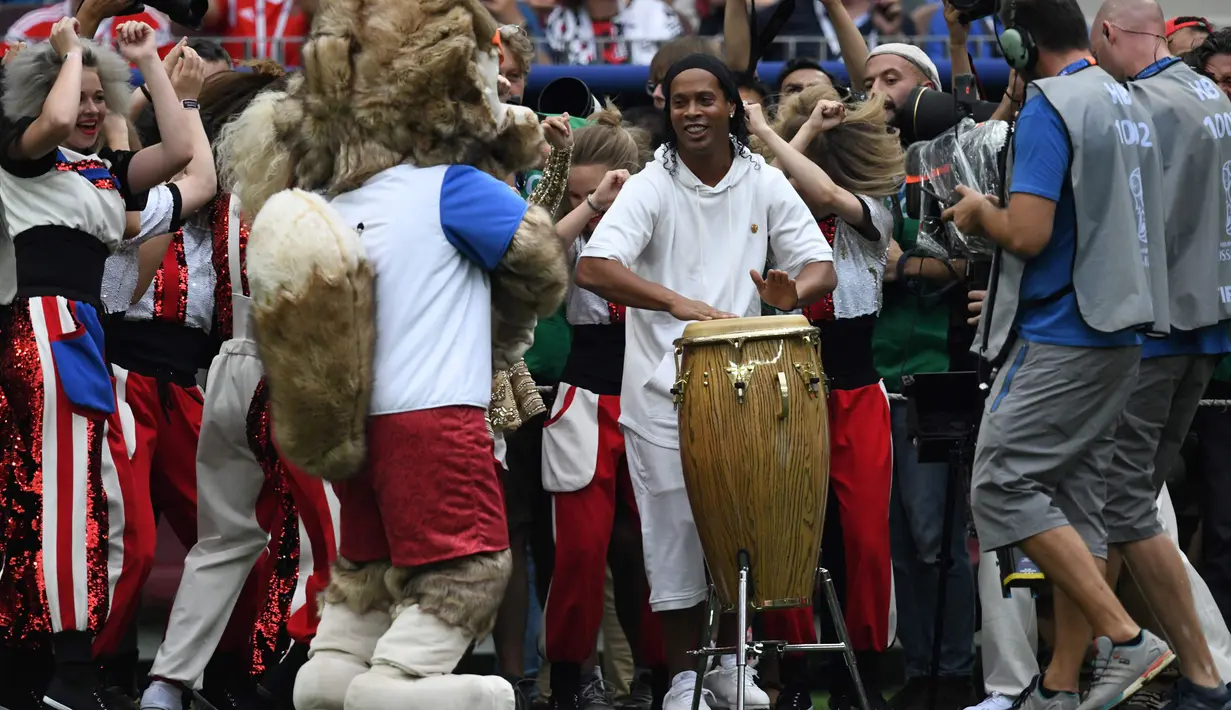 Legenda sepakbola Brasil, Ronaldinho menabuh jenis musik gendang, bongo pada seremonial final Piala Dunia 2018 di Stadion Luzhniki, Minggu (15/7). Penampilan Ronaldinho itu diikuti para penari yang bergerak beriringan di sampingnya. (AFP/CHRISTOPHE SIMON)