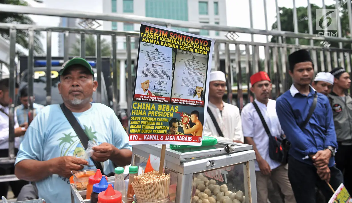 Massa Laskar Pembela Islam (LPI) saat mengawal pemeriksaan Habib Bahar bin Smith di depan Gedung Bareskrim Polri, Jakarta, Kamis (6/12). Massa membawa sejumlah poster tuntutan saat aksi. (Merdeka.com/Iqbal Nugroho)