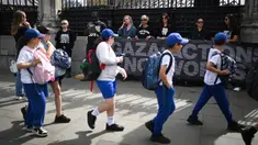 Anak-anak sekolah berjalan melewati aksi protes yang dilakukan oleh organisasi non-pemerintah Choose Love Europe di luar Gedung Parlemen di London, Inggris pada 29 Mei 2025. (Justin TALLIS/AFP)