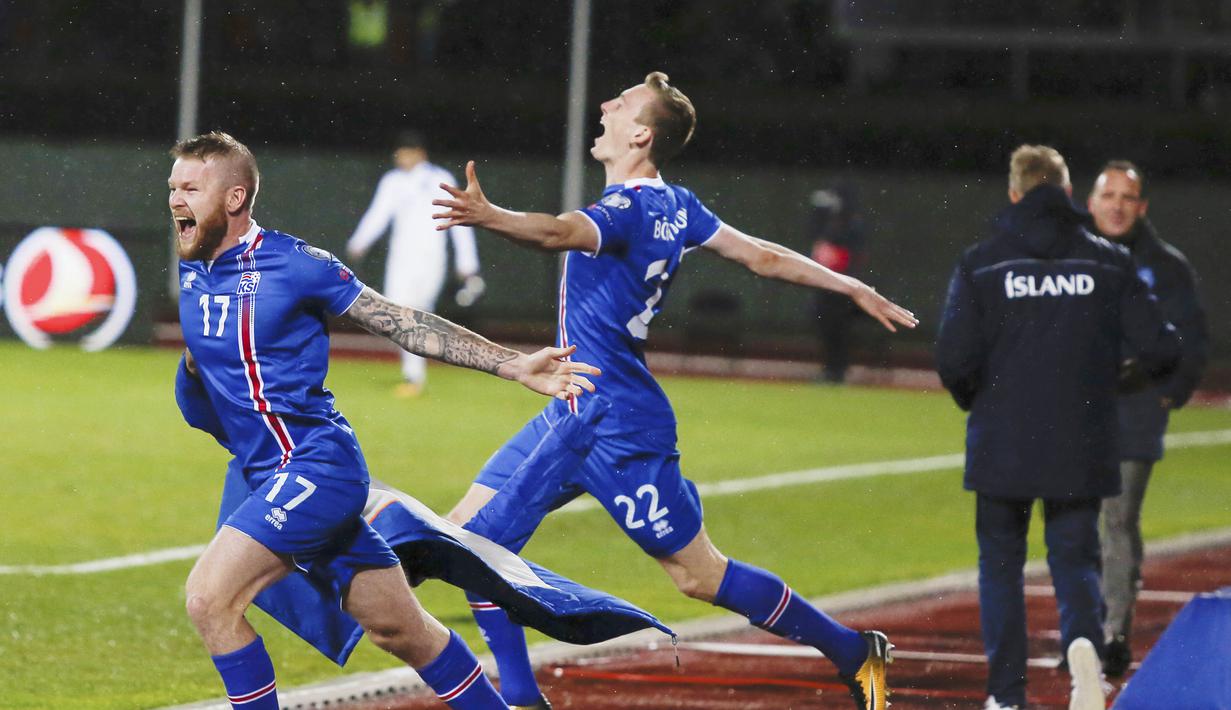 Pemain Islandia, Aron Einar Gunnarsson dan Jon Dadi Bodvarsson melakukan selebrasi usai memastikan negaranya lolos Piala Dunia 2018 di Stadion Laugardalsvöllur, Senin (9/10/2017). Islandia menang 2-0 atas Kosovo. (AP/Brynjar Gunnarsson)