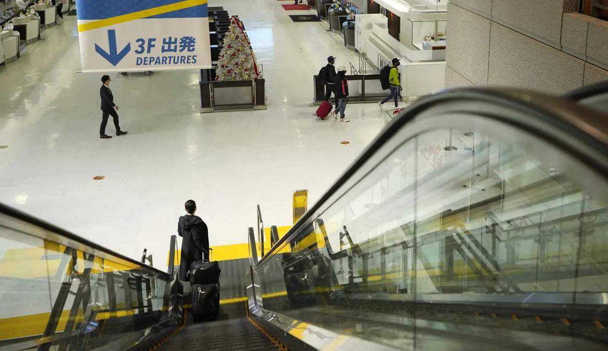 Seorang wanita turun dengan eskalator menuju check in counter di terminal keberangkatan Bandara Internasional Narita, timur Tokyo, Kamis (2/12/2021). Maskapai-maskapai internasional diminta menangguhkan reservasi baru pada semua penerbangan masuk ke Jepang hingga akhir Desember (AP Photo/Hiro Komae)
