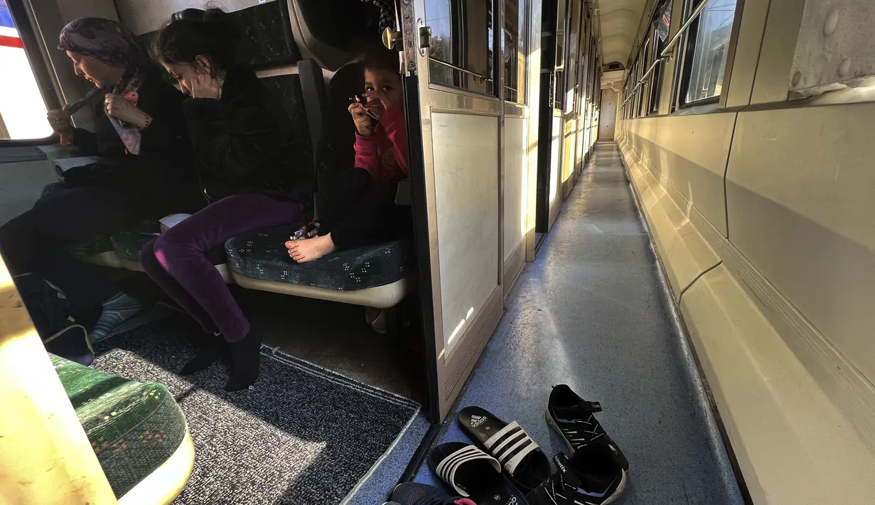 Seorang ibu Turki bersama putrinya duduk di kereta yang digunakan sebagai tempat berlindung setelah mereka kehilangan rumah akibat gempa dahsyat, di kota Iskenderun, Turki selatan, Selasa (14/2/2023). Duka menyelimuti korban gempa Turki dan Suriah, mereka tidak hanya kehilangan keluarga tetapi juga rumah tempat mereka berteduh. (AP Photo/Hussein Malla)