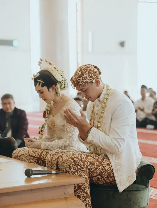 Rian Ardianto tampil gagah dengan beskap putih dengan detail bordir emas rancangan @wonghangtailor x @myrnamyura. [@morden.co].