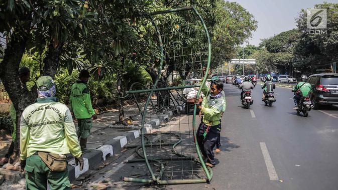 Petugas Suku Dinas Kehutanan Jakarta Pusat mengangkut pagar yang dirusak pengunjuk rasa usai demonstrasi di depan TPU Karet, Jakarta, Selasa (1/10/2019). Pengerusakan dilakukan pengunjuk rasa saat terlibat bentrok dengan polisi di kawasan tersebut. (Liputan6.com/Faizal Fanani)