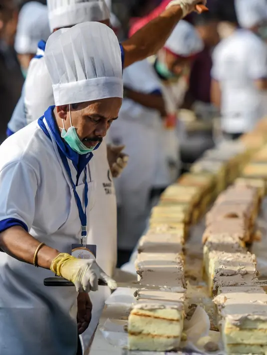 Seorang koki menyelesaikan kue sepanjang 6,5 km untuk kue terpanjang dunia, di Thrissur di negara bagian Kerala, India selatan (15/1/2020). Ratusan pembuat roti dan koki di India selatan membuat kue terpanjang di dunia. (AFP/Arun Sankar)