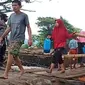 Warga Desa Waiburak, smelintasi jembatan darurat yang dibangun TNI/Polri pasca banjir bandang untuk membelih minyak tana di Kelurahan Waiwerang. (Liputan6.com/Dionisius Wilibardus)