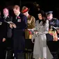 Meghan Markle dan tunangannya Pangeran Harry saat menghadiri kebaktian Anzac Day di Hyde Park Corner di London (25/4). Anzac Day adalah hari peringatan kebangsaan yang dirayakan di Australia dan New Zealand. (Toby Melville/Pool Photo via AP)