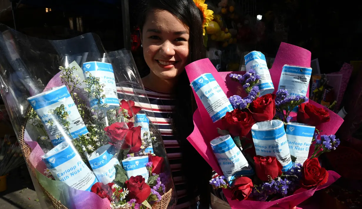 Pedagang menunjukkan karangan bunga yang dihiasi dengan masker pada hari Valentine di sebuah pasar bunga di Manila (14/2/2020). (AFP Photo/Ted Aljibe)