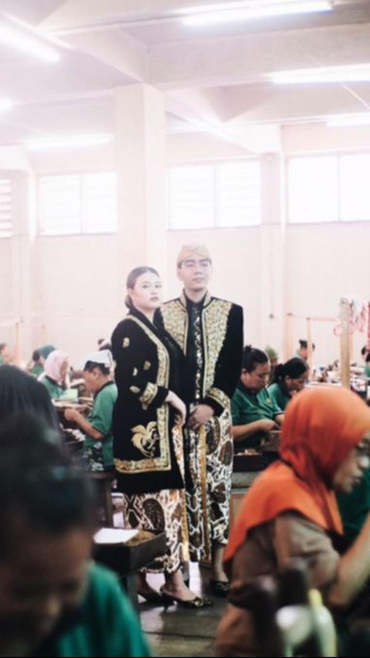 Aurel dan Graha erpose di tengah-tengah pekerja pabrik yang sedang melinting rokok kretek.