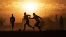 Orang-orang bermain sepak bola di lapangan berdebu di Soweto, Afrika Selatan, 19 Agustus 2020. Presiden Afrika Selatan Cyril Ramaphosa mengumumkan bahwa seluruh negara akan melakukan lockdown level 2 mulai hari Selasa. (AP Photo/ Themba Hadebe)