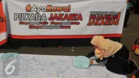 Seorang mahasiswa memasang poster saat melakukan aksi kawal Pilkada DKI 2017 di Jakarta, Minggu (5/2). Mereka mengajak warga untuk mengawal Pilkada DKI agar tidak terjadi kecurangan dan mengajak untuk tidak golput. (Liputan6.com/Angga Yuniar)