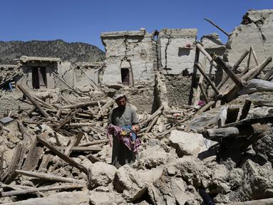 Seorang pria Afghanistan menggendong anaknya di tengah kehancuran setelah gempa bumi di desa Gayan, di provinsi Paktika, Afghanistan, Jumat, 24 Juni 2022. Gempa bumi dahsyat mengguncang Afghanistan pada Rabu 22 Juni 2022 dini hari, kekuatannya dilaporkan mencapai magnitudo 6,1. (AP Photo/Ebrahim Nooroozi)