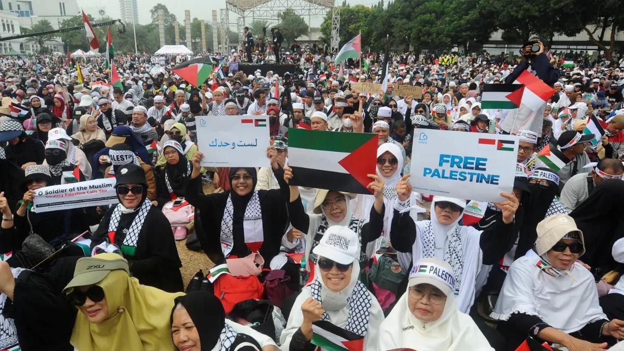 Warga membentangkan bendera Palestina saat mengikuti aksi bela Palestina di Masjid Al Azhar, Jakarta Selatan, Minggu (15/10/2023).