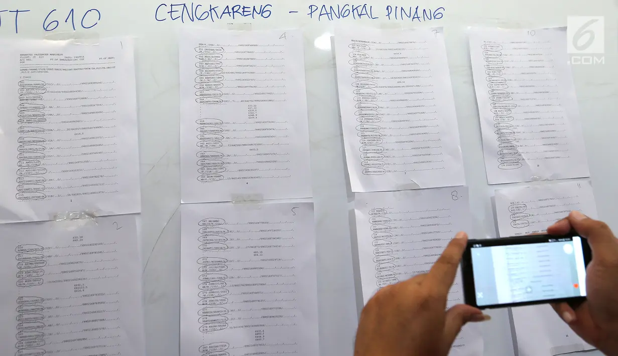 Pengunjung mengambil gambar daftar nama penumpang pesawat Lion Air JT 610 di crisis center Bandara Soekarno Hatta, Tangerang, Senin (29/10). Pesawat rute Jakarta-Pangkal Pinang itu dipastikan jatuh di laut utara Karawang (Liputan6.com/Fery Pradolo)
