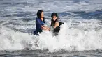 Dua wanita menikmati ombak di sepanjang pantai dekat Pulau Enoshima di pantai Prefektur Kanagawa, barat daya Tokyo (13/8/2019). Enoshima adalah pulau lepas pantai kecil, sekitar 4 km di sekelilingnya, di mulut Sungai Katase yang mengalir ke Teluk Sagami di Prefektur Kanagawa, Jepang. (AFP Photo/Char