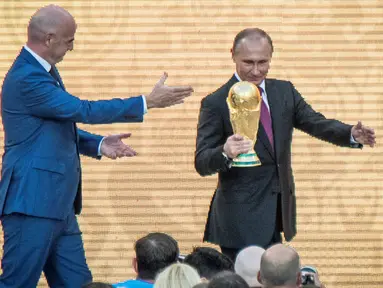 Presiden Rusia Vladimir Putin memegang trofi Piala Dunia dalam pembukaan upacara  "FIFA World Cup Trophy Tour" di stadion Luzhniki di Moskow (9/9). Piala Dunia 2018 adalah Piala Dunia FIFA ke-21. (AFP Photo/Mladen Antonov) 