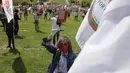 Seorang wanita memegang bendera serikat pekerja transportasi dan mengenakan masker saat memperingati Hari Buruh di tengah pandemi COVID-19 di Lisbon, Portugal, Jumat (1/5/2020). Aksi ini sudah mendapat persetujuan Kementerian Kesehatan dan Dalam Negeri Portugal. (AP Photo/Armando Franca)