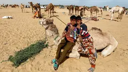 Dua joki cilik, Sayed Mohamed (11) dan Mahmoud Mahmed (13) menunggu pembukaan Festival Balapan Unta Internasional di gurun Sarabium, Ismailia, Mesir, 12 Maret 2019. Balap unta tersebut dilakukan oleh sejumlah anak-anak. (REUTERS/Amr Abdallah Dalsh)