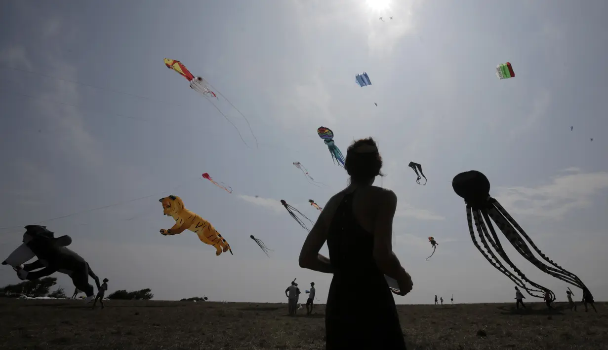 Seorang wanita melihat layang-layang dalam Varvara Kite Fest di Desa Varvara, pesisir Laut Hitam, Bulgaria, Jumat (27/8/2021). Penyelenggara Varvara Kite Fest Andrey Kulev mengatakan bahwa menerbangkan layang-layang seperti melepaskan semua masalah Anda di langit. (AP Photo/Valentina Petrova)