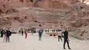 Wisatawan jalan-jalan saat mengunjungi kota arkeologi Petra, Yordania, Kamis (21/11/2019). Bangunan-bangunan di kota ini didirikan dengan memahat dinding-dinding batu di Wadi Araba, lembah bercadas di Yordania. (AHMAD ABDO/AFP)