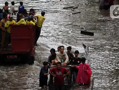 Warga melintasi banjir yang merendam kawasan Green Garden, Jakarta Barat, Selasa (25/2/2020). Hujan yang mengguyur kawasan Jakarta membuat kawasan tersebut tergenang banjir setinggi 60-80 cm. (Liputan6.com/Johan Tallo)