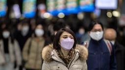 Seorang wanita memakai masker berjalan di stasiun Shinagawa di Tokyo (18/1/2022). Jepang melaporkan rekor tertinggi infeksi Covid-19 baru yang dipicu oleh varian Omicron. (AFP/Philip Fong)