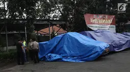 Terpal menutupi kendaraan yang terparkir di halaman Polsek Ciracas seusai perusakan dan pembakaran di Jakarta, Rabu (12/12). Belum diketahui tujuan massa mendatangi Polsek Ciracas hingga terjadi pembakaran pada dinihari tadi (Liputan6.com/Herman Zakharia)