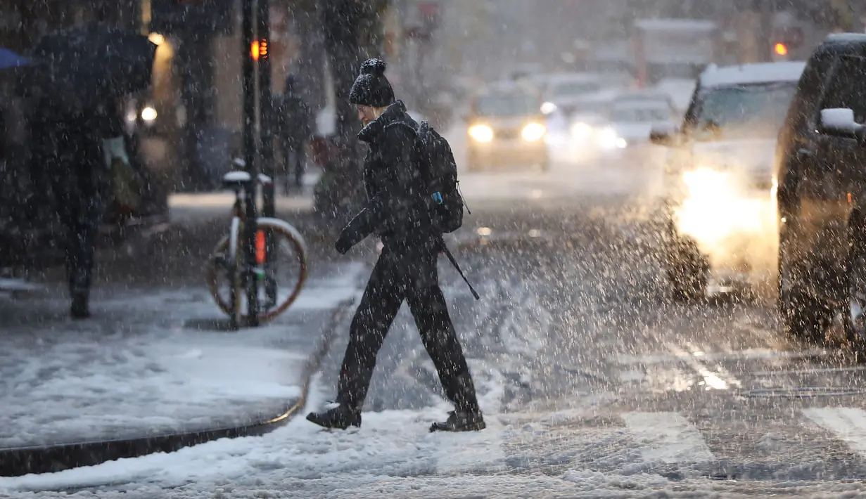 Pejalan kaki melintas saat salju mulai turun di Manhattan, New York, Kamis (15/11). Layanan Cuaca Nasional memprediksi hujan salju pertama pada awal musim dingin itu akan mencapai ketebalan 2-4 inci. (Angela Weiss / AFP)