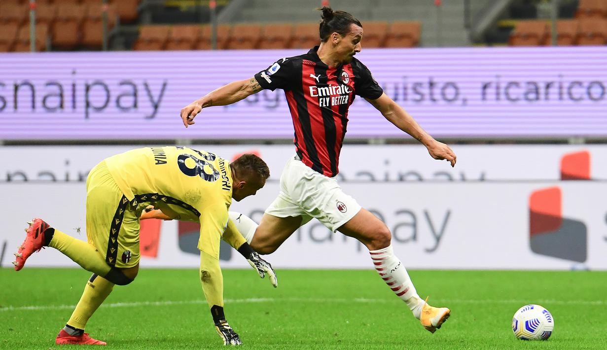 Penyerang AC Milan, Zlatan Ibrahimovic, melewati kiper Bologna, Lukasz Skorupski, pada laga Liga Italia di Stadion San Siro, Selasa (22/9/2020) dini hari WIB. AC Milan menang 2-0 atas Bologna. (AFP/Miguel Medina)