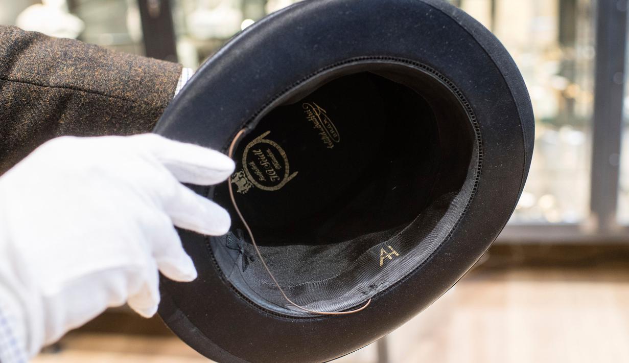 Pegawai memegang topi berinisial AH sebelum lelang memorabilia Nazi di Grasbrunn, Jerman, Rabu (20/11/2019). Menurut rumah lelang Hermann Historica dalam websitenya, topi Adolf Hitler tersebut terjual dengan harga 50 ribu euro atau sekitar Rp 781,7 juta. (Matthias Balk/dpa via AP)