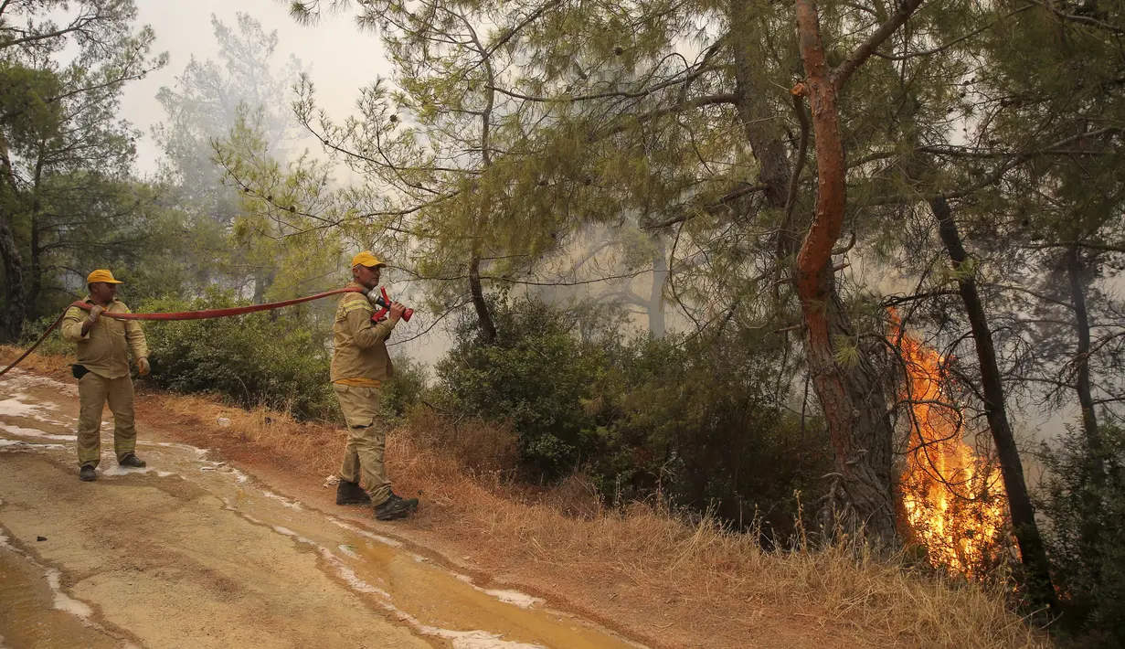 Petugas pemadam kebakaran bekerja di daerah Mazi yang diselimuti asap saat kebakaran hutan berguling menuruni bukit menuju pantai di Bodrum, Mugla, Turki, Minggu (1/8/2021). Menurut para pejabat, lebih dari 100 kebakaran hutan telah dikendalikan di Turki. (AP Photo/Emre Tazegul)