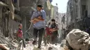 Para pria menggendong bayi saat berjalan melewati puing-puing bangunan yang hancur usai serangan udara di daerah yang dikuasai pemberontak di Salihin, Aleppo, Suriah, 11 September 2016. (Photo by Ameer al-HALBI/AFP)