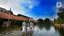 Siswa berjalan melewati banjir yang menggenangi halaman  sekolah di SMAN 4 Tangsel, Pondok Ranji, Tangerang Selatan, Banten, Selasa (14/6/2022). Tiga  pekan lebih banjir merendam lapangan sekolah itu dikarenakan tertutupnya saluran air oleh sampah yang berasal dari tempat pembuangan sampah (TPS) ilegal. (merdeka.com/Arie Basuki)