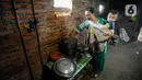 Warga menggendong bayi saat memasak menggunakan energi yang berasal dari biogas di Desa Dompyong, Trenggalek, Jawa Timur, Minggu (3/9/2023). (merdeka.com/Arie Basuki)