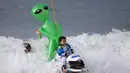 Ekspresi seorang anak dengan balon aliennya mengikuti konstes surfing Haunted Heats Halloween di Santa Monica, California, (29/10). Acara ini untuk merayakan hari Halloween yang jatuh pada tanggal 31 Oktober. (REUTERS/Lucy Nicholson)