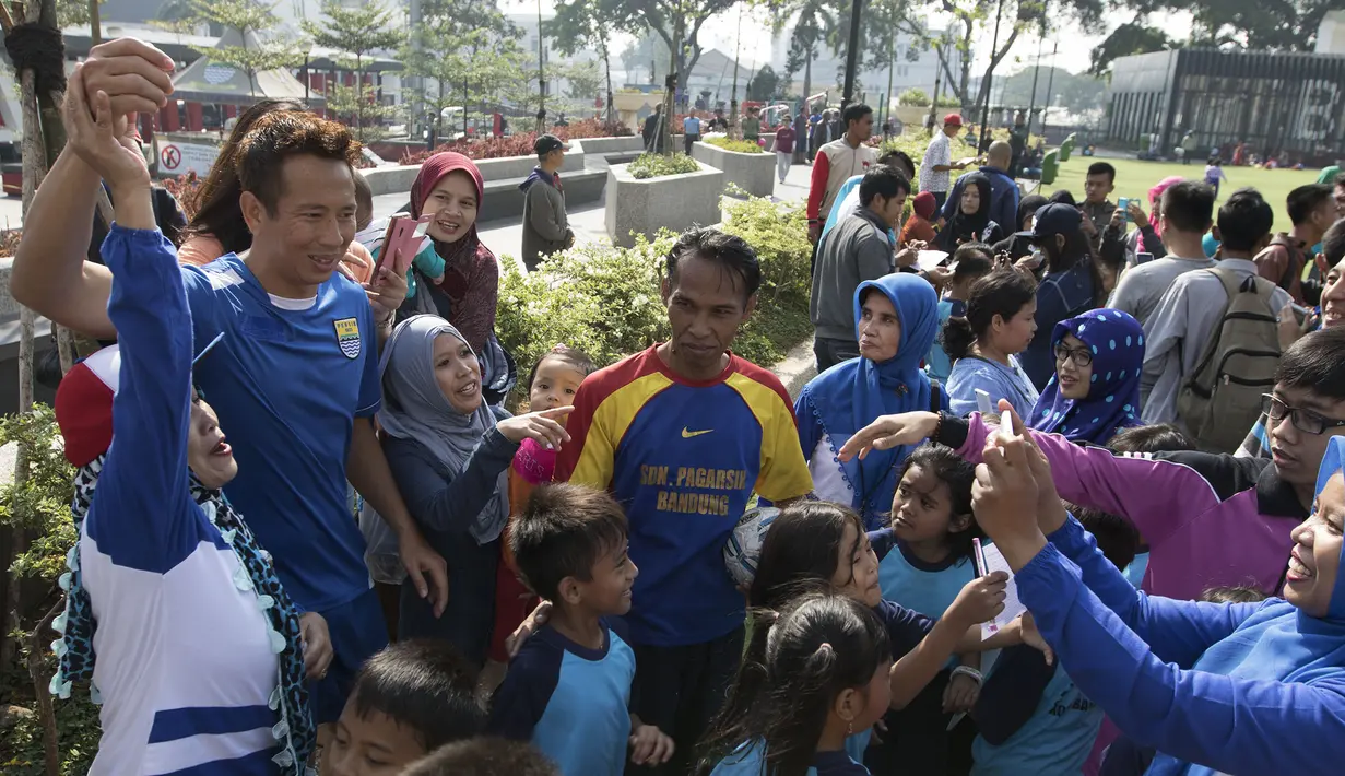 Kiper Persib, I Made Wirawan tertawa bersama para penggemar yang meminta foto bersama usai latihan di Alun-alun Kota Bandung, Jawa Barat, Kamis (10/9/2015). (Bola.com/Vitalis Yogi Trisna)