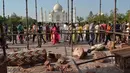 Wisatawan berjalan melewati reruntuhan puing-puing dari pilar Taj Mahal yang roboh di pintu masuk bangunan ikonik tersebut di Agra, India, Kamis (12/4). Dua buah pilar menara Taj Mahal rusak akibat dihantam angin kencang. (AP/Pawan Sharma)