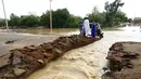 Sejumlah warga berdiri di dekat jalan yang tergenang banjir di Khartoum, Sudan (3/8/2020). Sudan dilanda banjir baru-baru ini akibat hujan lebat. (Xinhua/Mohamed Khidir)